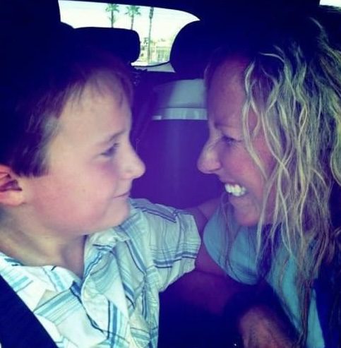A joyful moment between a smiling woman and a boy inside a car.