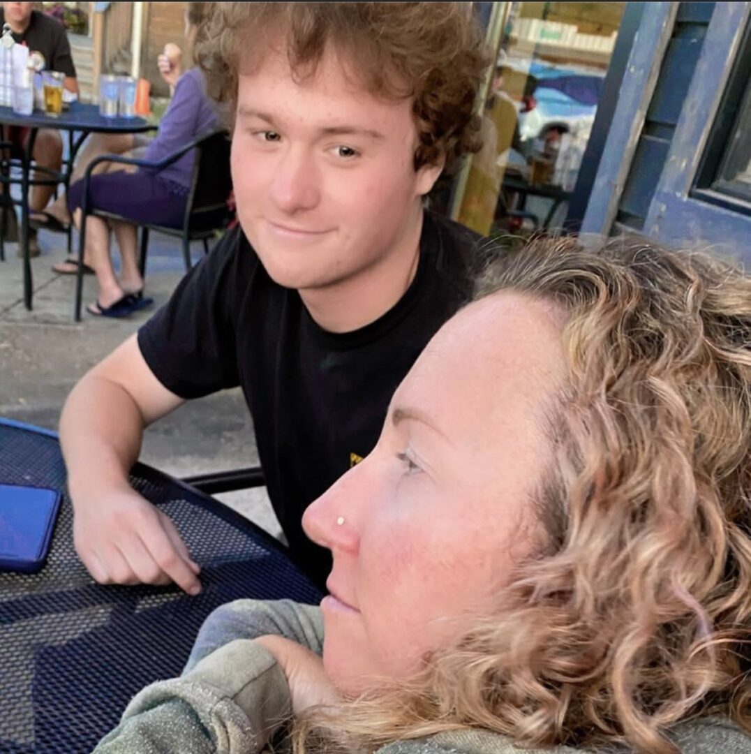 Two people sitting together at a table, one looking at the camera.