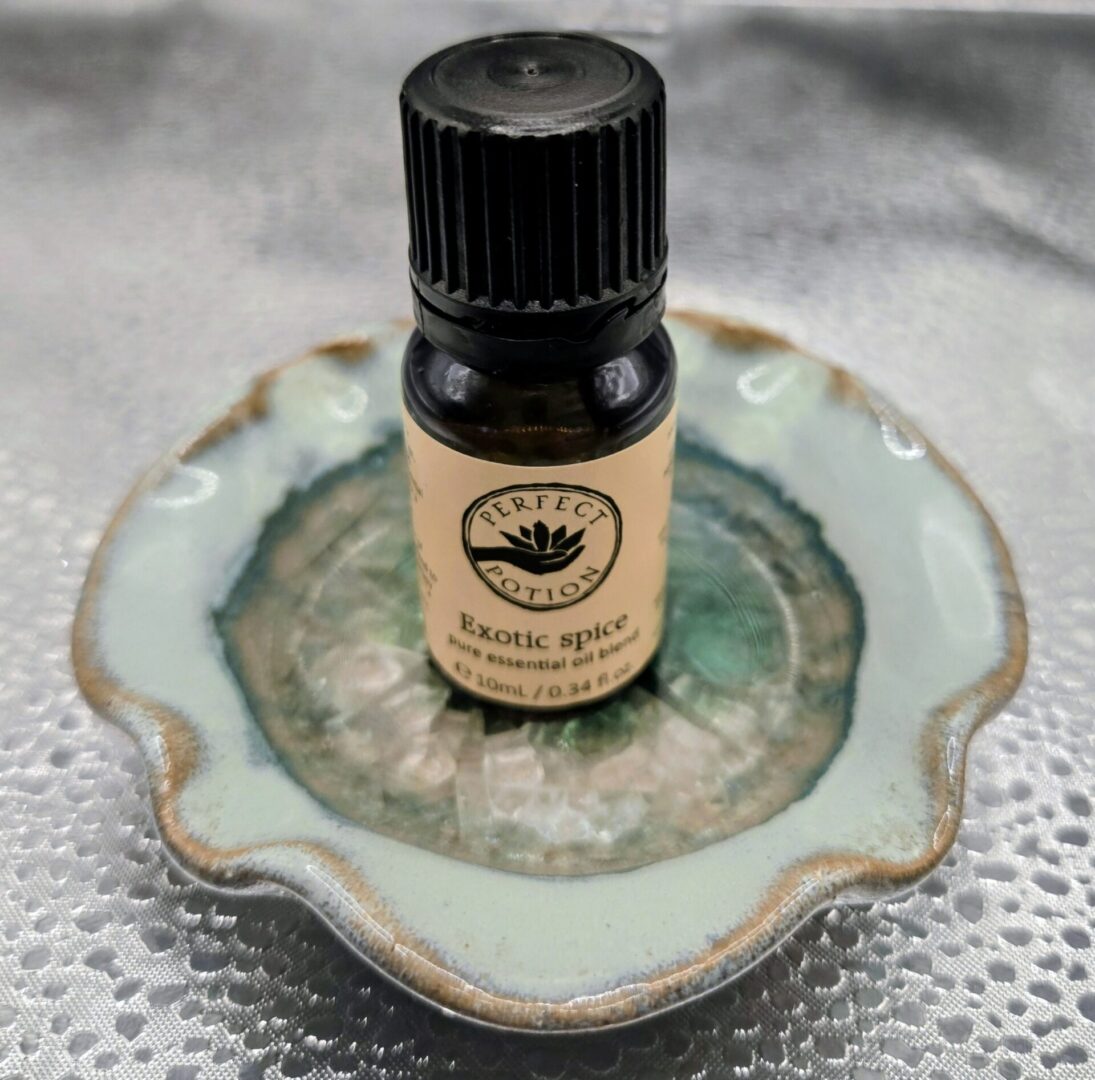 Bottle of Perfect Potion Exotic Spice essential oil on a decorative dish.