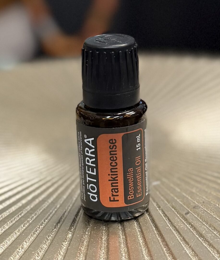 A small bottle of doTERRA Frankincense essential oil on a textured surface.