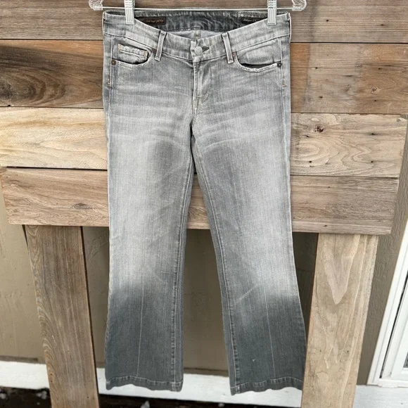 Gray jeans with a gradient fade from light to dark hanging on a wooden backdrop.