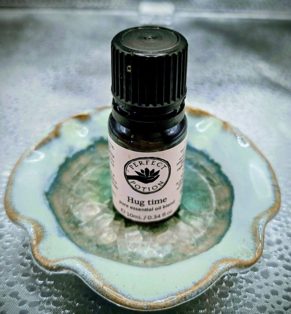 A small bottle of 'Hug time' essential oil blend on a decorative dish.