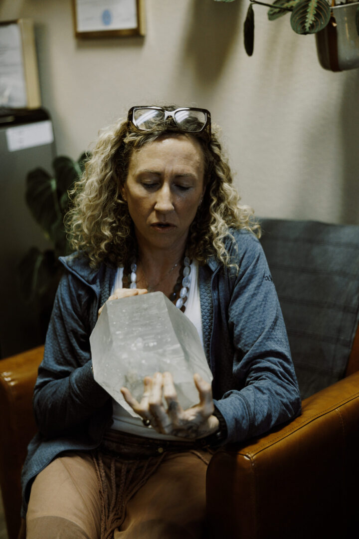 Woman sitting and examining a large translucent crystal.