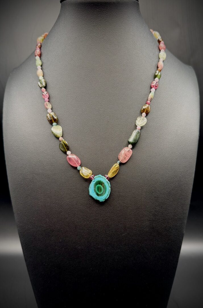 Colorful beaded necklace with a turquoise pendant on display.