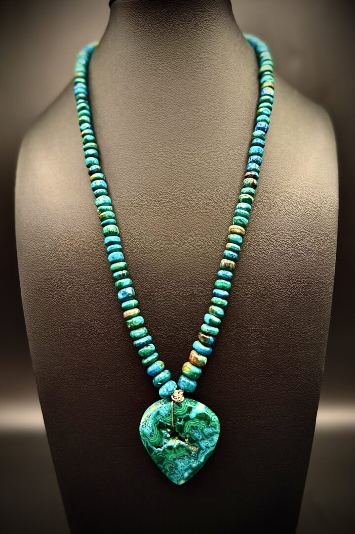 Turquoise beaded necklace with a heart-shaped pendant on display.