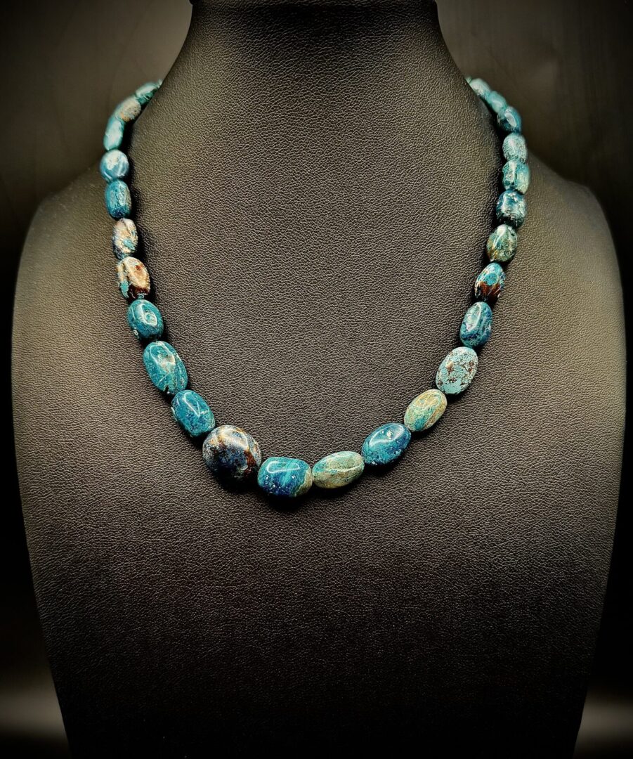 A turquoise stone bead necklace displayed on a black bust.