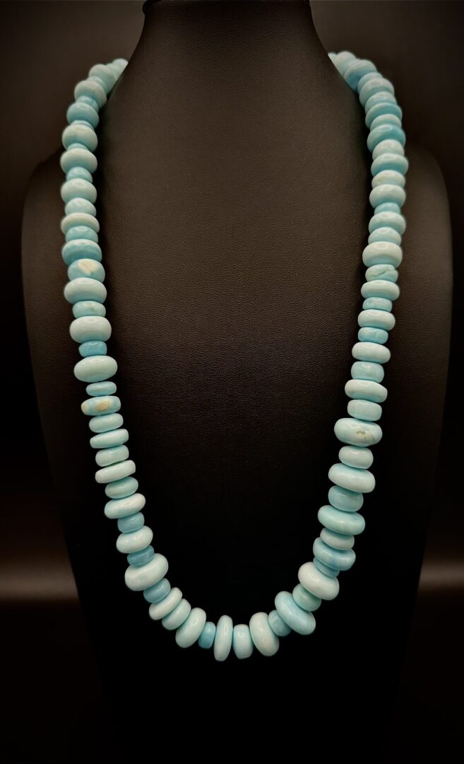 Elegant necklace with graduated light blue beads on black display.