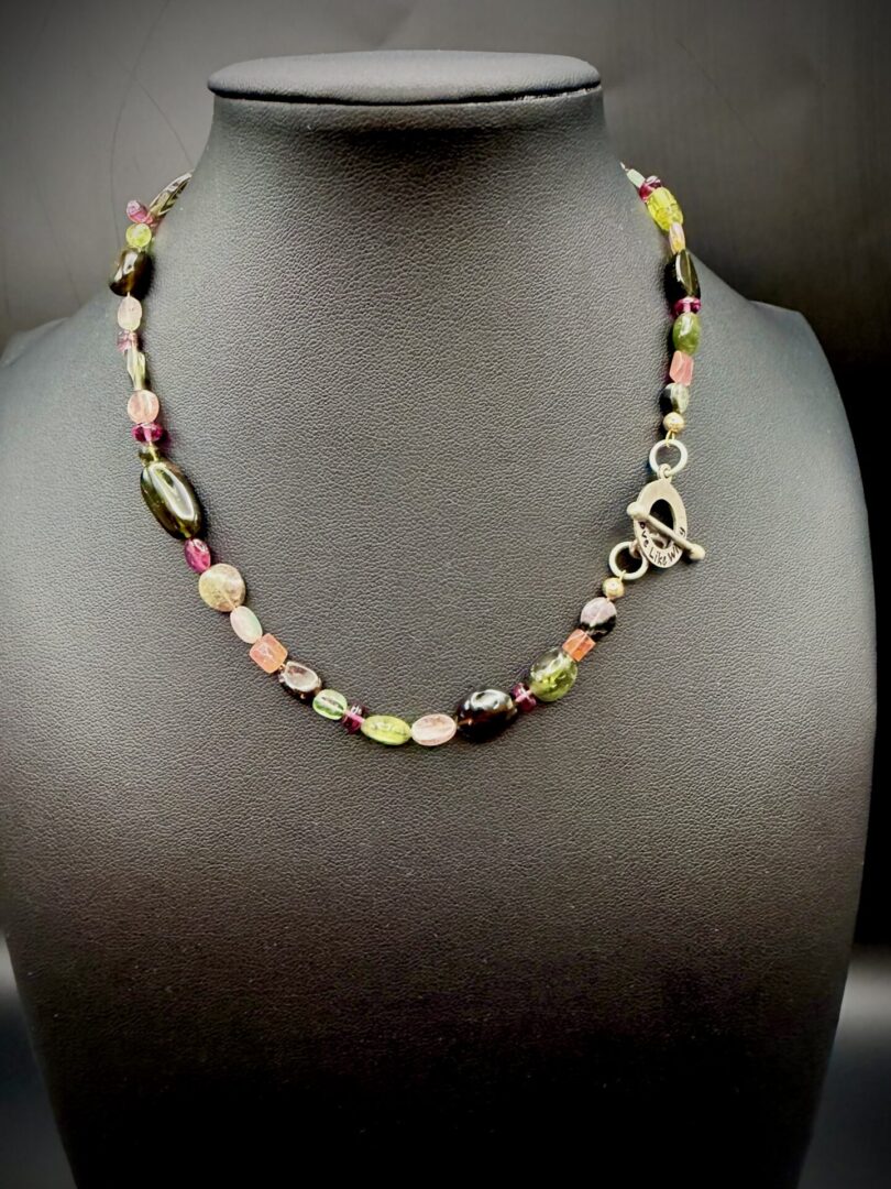 Colorful beaded necklace with a silver toggle clasp on a black display.