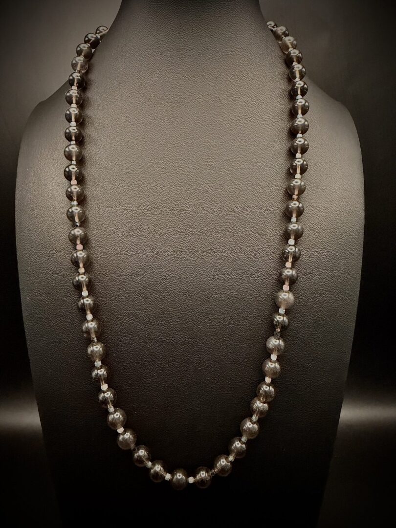Elegant black beaded necklace displayed on a black stand.