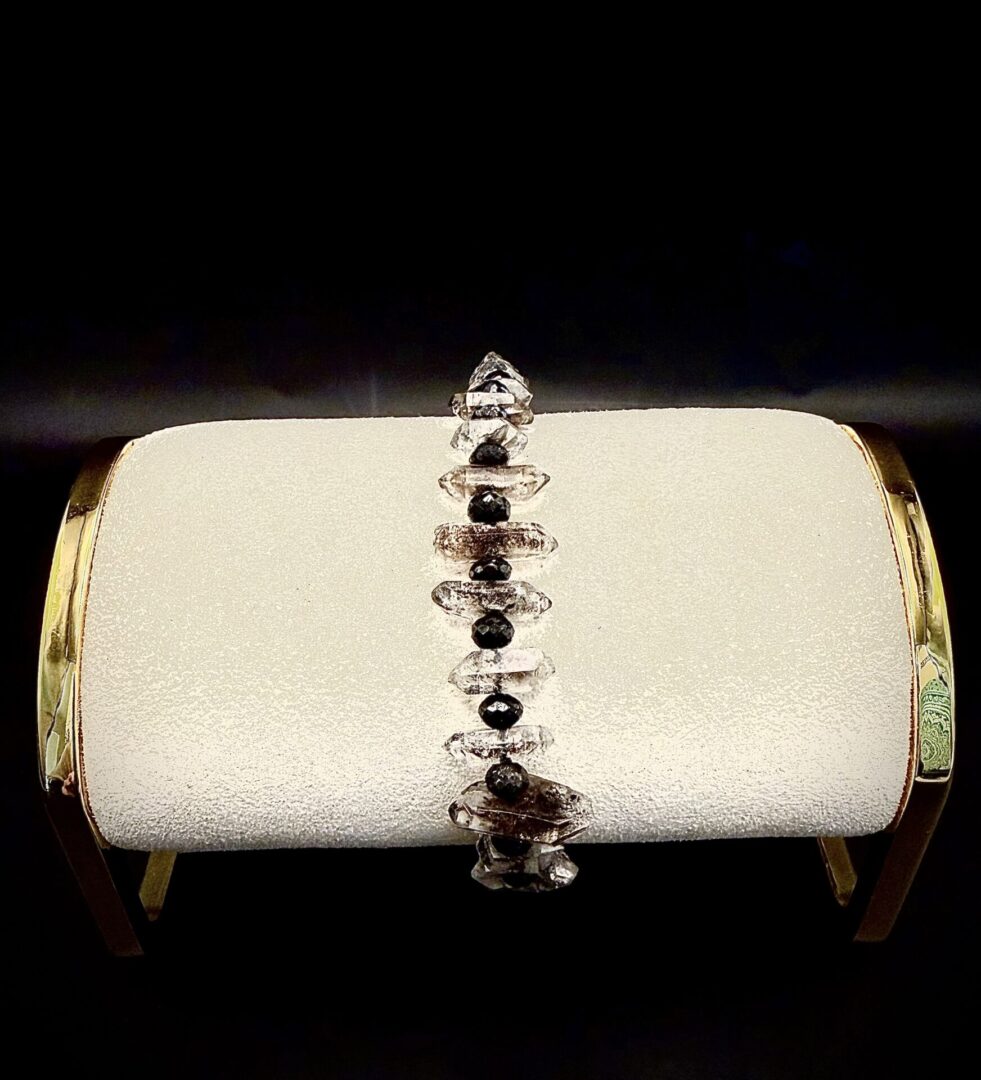 Elegant bracelet with clear and black beads displayed on a white textured holder.