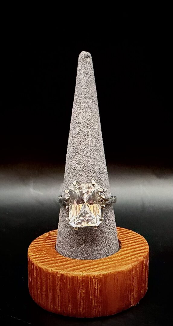 Elegant ring with a large rectangular gemstone on a velvet cone stand.