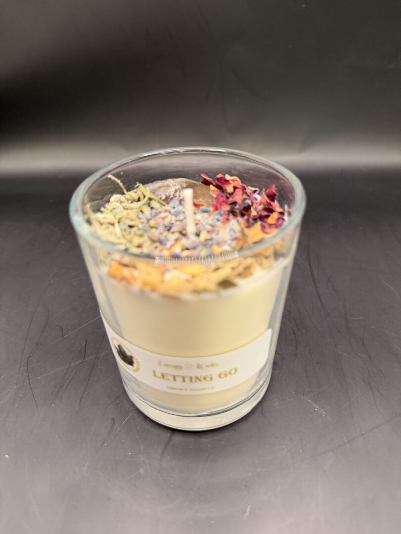 A decorative scented candle labeled 'Letting Go' with dried flowers on top.