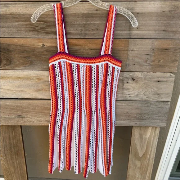 Colorful striped crochet dress hanging on a wooden background.