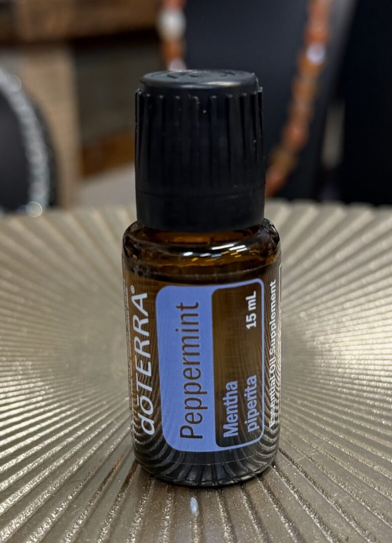 A small bottle of doTERRA Peppermint essential oil on a textured surface.