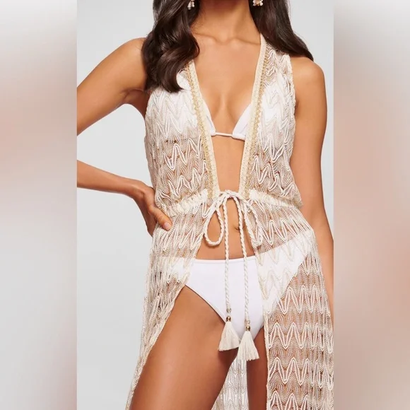 Woman wearing a white bikini and a sheer, patterned cover-up with tassel ties.