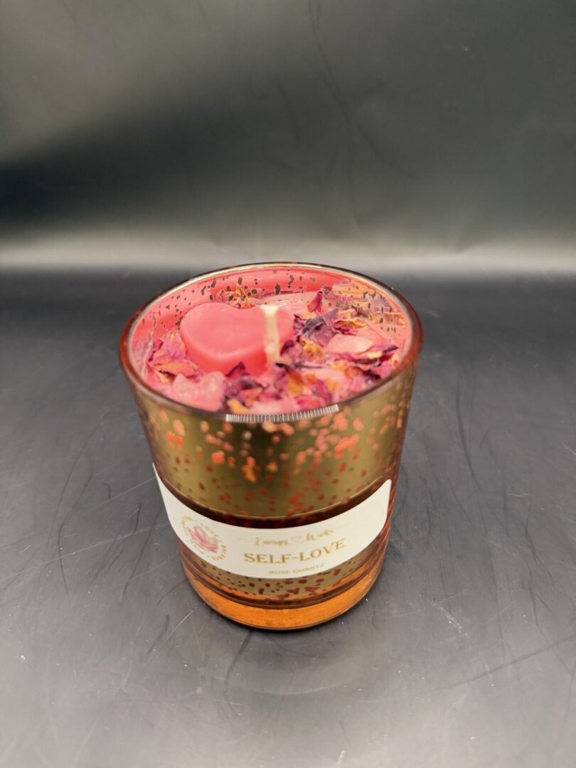 Decorative self-love candle with rose quartz and petals in a speckled glass holder.