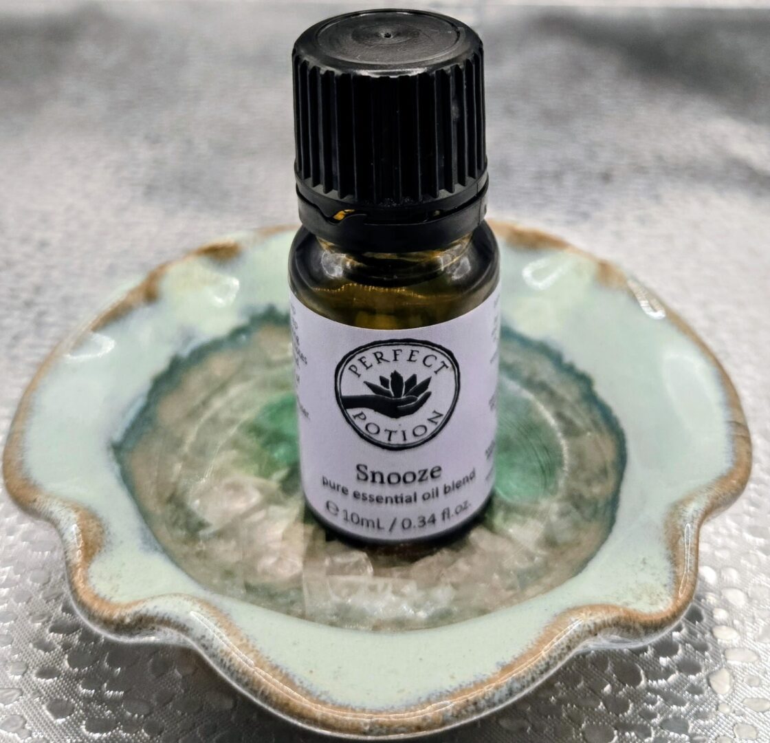 A bottle of Perfect Potion Snooze essential oil on a decorative dish.