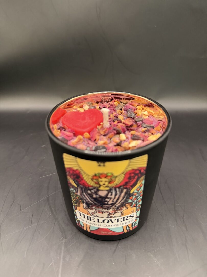 Decorative candle with heart and floral design, labeled 'The Lovers' for love and commitment.