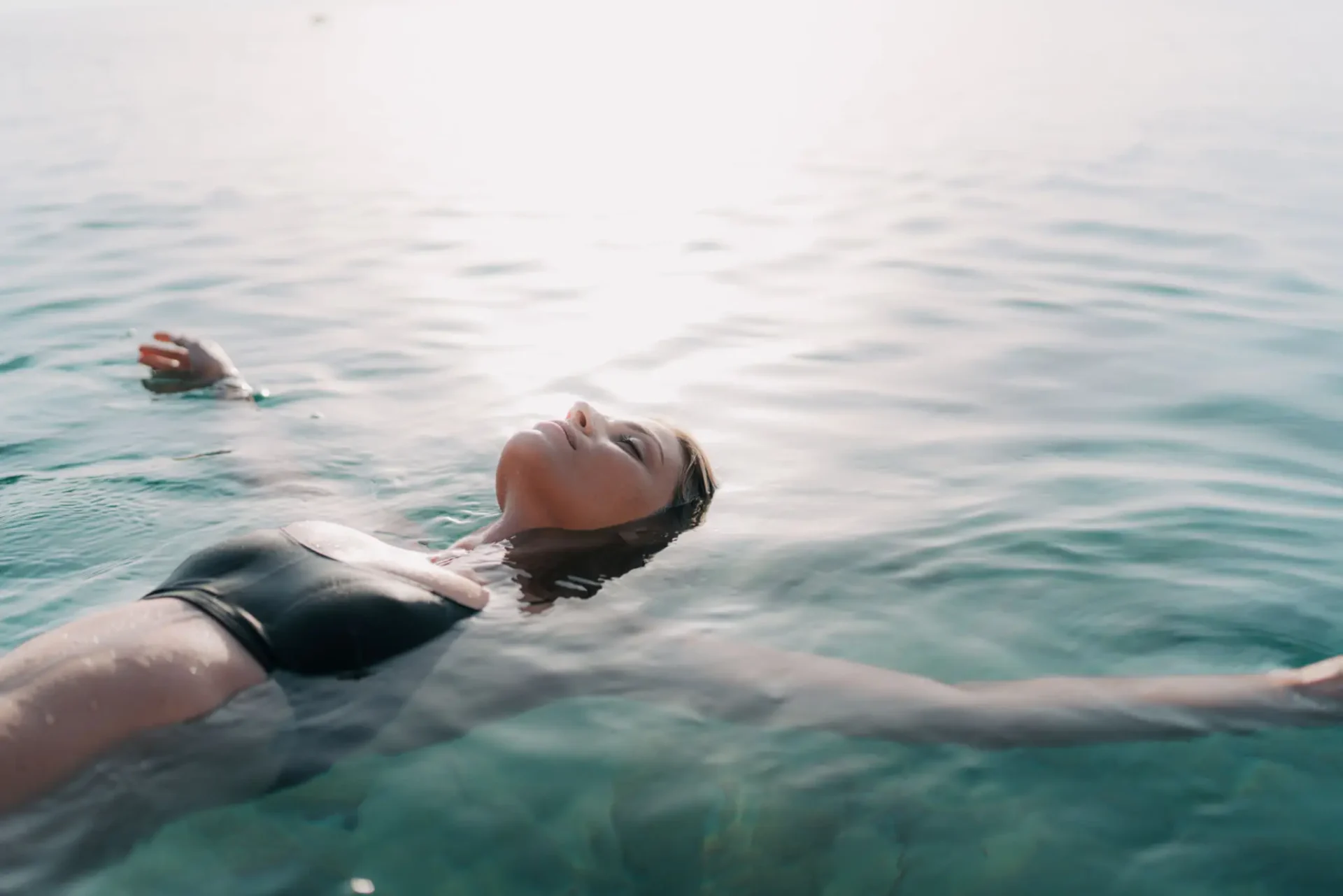 Woman floating peacefully on water with arms outstretched.